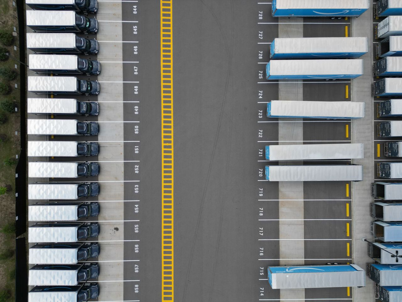 our-journey-03 Top-down view of lined-up trucks at a logistics parking lot, showing organized transportation hub.